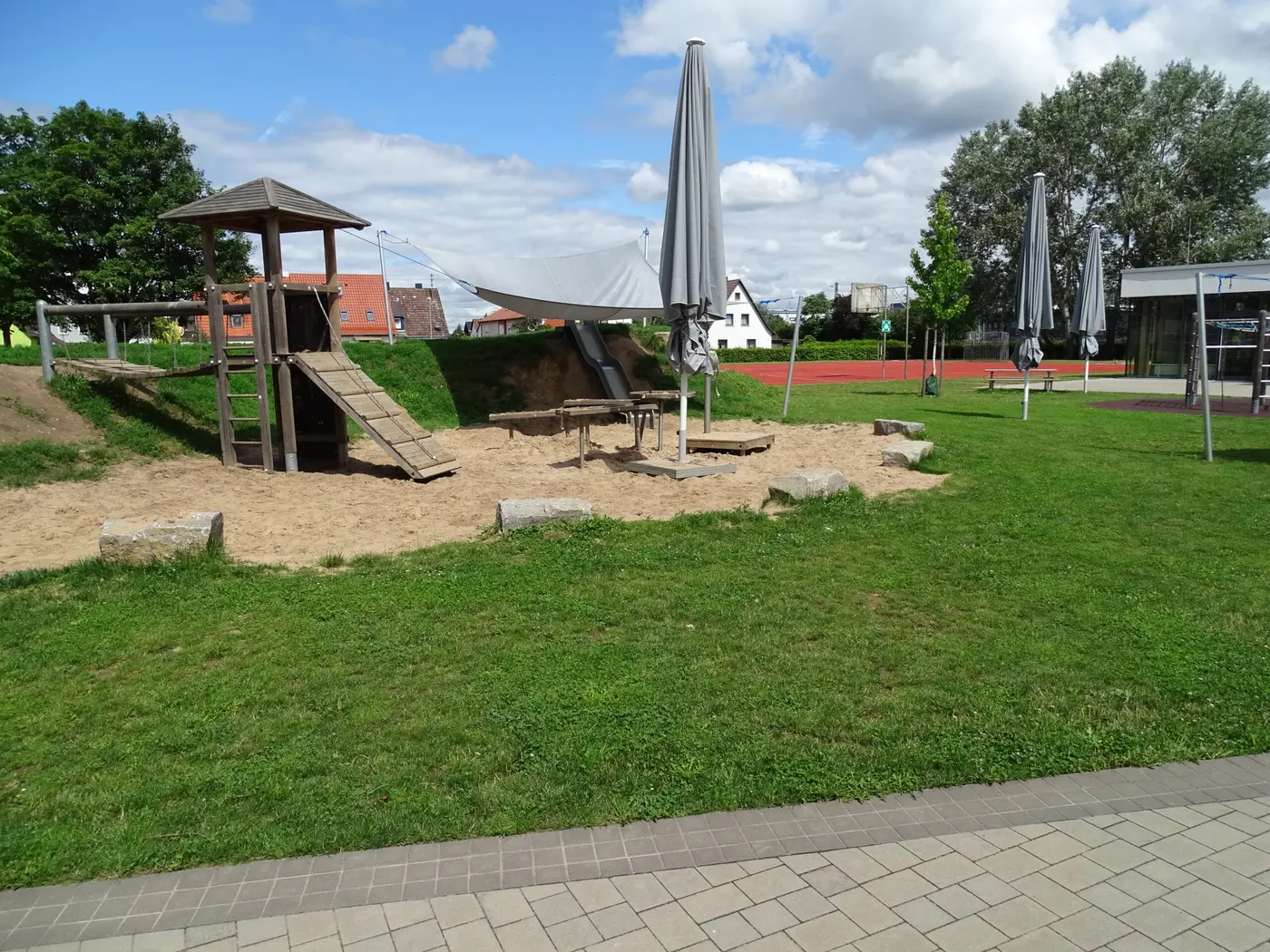 Holz-Spielturm mit Rutsche und Sandbereich unter Sonnensegeln